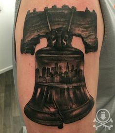 a tattoo on the arm of a man with a black and white image of a bell