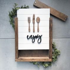 the word enjoy spelled with forks and spoons in front of a wooden sign that says enjoy