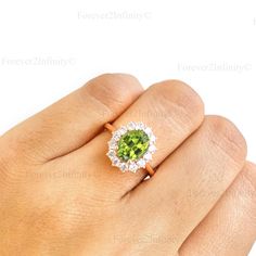 a woman's hand holding a ring with a green and white stone in it