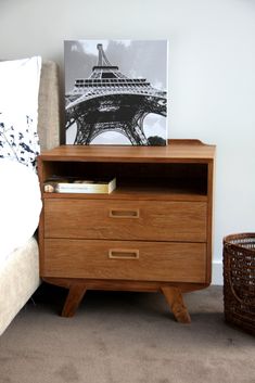 a wooden dresser with drawers in front of the eiffel tower print on it