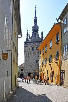 people are walking down the cobblestone street in an old european city with tall buildings