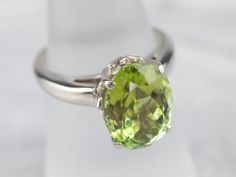 This classically designed green tourmaline solitaire ring is timeless and goes with everything! This simple and elegant ring features a polished white gold mounting. The green tourmaline is a rich lime green, beautifully protected in the simple four-prong setting.Metal: 14K White GoldGem: Green Tourmaline 5.38 CaratsGem Measurements: 12.8 x 9.4 mm, OvalRing Size: 6.50Marks: “SGI 14K” Stamped on the inside band Timeless Green Solitaire Ring, Classic Solitaire Peridot Ring, Classic Peridot Green Rings, Classic Green Peridot Ring, Classic Peridot Solitaire Jewelry, Classic Solitaire Peridot Jewelry, Elegant Peridot Solitaire Ring, Elegant Solitaire Peridot Ring, Classic Peridot Ring For Formal Occasions