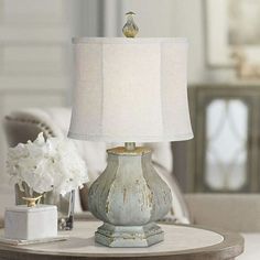 a table lamp sitting on top of a wooden table next to a white flower vase