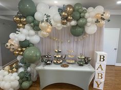 a table topped with lots of balloons next to a white and green cake stand on top of a hard wood floor