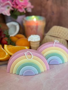 two rainbow shaped cookies sitting on top of a table next to oranges and strawberries