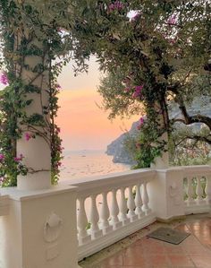 an outdoor balcony overlooking the ocean with flowers and greenery on the balconies