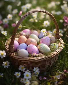 a basket filled with lots of colorful eggs on top of a grass covered field next to flowers