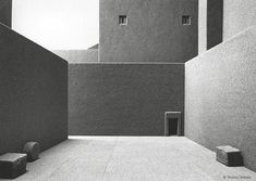 an empty courtyard with benches and buildings in the backgroung, black and white photograph