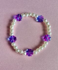 Stretch beaded bracelet white pearl beads with purple glass flower beads. Size Medium. 7 inches in length White Beaded Pearl Bracelet With Flower Design, Purple Beaded Pearl Bracelet With Round Beads, Purple Beaded Pearl Bracelet As Gift, Handmade Purple Pearl Bracelet With Round Beads, Purple Pearl Bracelet As A Gift, White Beaded Pearl Bracelet With Flower Shape, White Beaded Flower Pearl Bracelet, Purple Beaded Pearl Bracelet For Gift, Purple Beaded Pearl Bracelet Gift