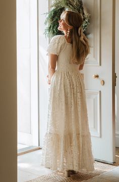 a woman standing in front of a door wearing a dress