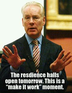 a man in a suit and tie holding his hands up to the side while talking