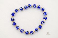 Esta es una auténtica y original pulsera Blue Evil Eye. Una de las razones más comunes para usar el brazalete contra el mal de ojo es protegerse de todo mal o negatividad en su vida.

 El ojo de Nazar se considera uno de los símbolos más poderosos del mundo. Trae protección, paz y buena suerte a tu vida colgando este exclusivo dije de mal de ojo que te mantendrá a salvo de cualquier negatividad.

 Esta pulsera es perfecta para alguien que quiere un regalo económico para ella o para otra persona. Esta pulsera hecha a mano está hecha a mano con cuentas azules de 6 mm y cuentas doradas de 6 mm, cuentas de metal de cobre bañadas en oro falso. Todos los materiales son duraderos y durarán años. Puedes usarlo con cualquier atuendo o ponerlo en la mesa de tu oficina para traerte buena suerte. Blue Hypoallergenic Spiritual Bracelets, Blue Adjustable Evil Eye Bracelet, Adjustable Blue Evil Eye Bracelet, Adjustable Blue Evil Eye Bracelet For Spiritual Purposes, Blue Evil Eye Jewelry For Meditation, Adjustable Blue Spiritual Evil Eye Bracelet, Symbolic Blue Bracelet Jewelry, Blue Beaded Bracelets With Evil Eye, Blue Round Evil Eye Bracelets