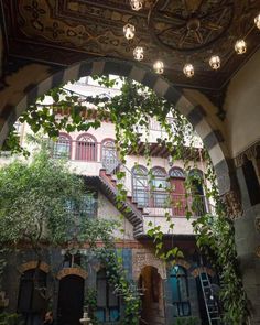 an ornate building with lots of windows and plants growing on the outside, along with stairs leading up to the second floor