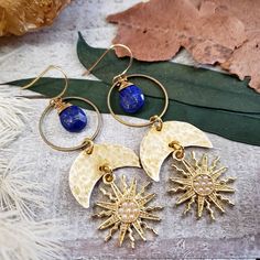 "Introducing: The \"Astraea\" collection PART 2. The Astraea features hammered metals, celestial elements and geometric shapes that form a gorgeous collection inspired by Greek goddess Astraea. Perfectly completed with deep blue lapis lazuli gemstone drops - Brass metal materials - 14k gold plated earring hooks - Gold plated brass Sun charms with tiny faux pearl inlay - Rubber ear nut backers included - 10mm lapis lazuli gemstone 2021©Wanderlust Hearts designs All Rights Reserved. WanderlustHear Mystical Brass Jewelry With Sun And Moon Design, Bohemian Lapis Lazuli Earrings, Mystical Sun And Moon Brass Jewelry, Handmade Celestial Metal Earrings, Celestial Bronze Jewelry With Moon Phase, Mystical Bronze Brass Jewelry, Mystical Brass Dangle Jewelry, Handmade Celestial Brass Earrings, Nickel-free Gold Lapis Lazuli Earrings