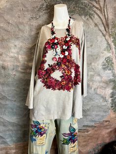 a mannequin is standing next to a white shirt with flowers and beads on it