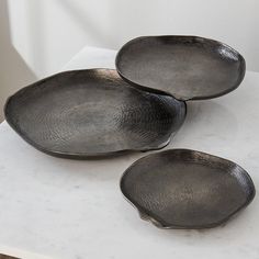 three metal plates sitting on top of a white counter