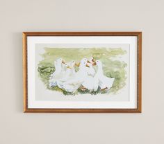 watercolor painting of three white ducks in grassy area next to wall with framed artwork