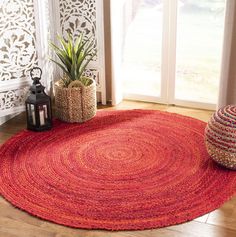 a red rug in front of a window next to a potted plant