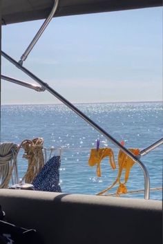 clothes hanging out to dry on the deck of a boat in the ocean with blue sky and water behind it