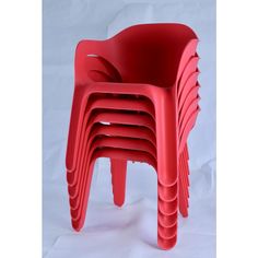 a stack of red plastic chairs sitting on top of a white floor next to each other