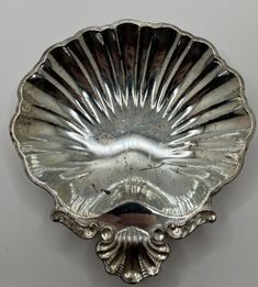 an antique silver plate with scallop design on the bottom and sides, mounted on a wall