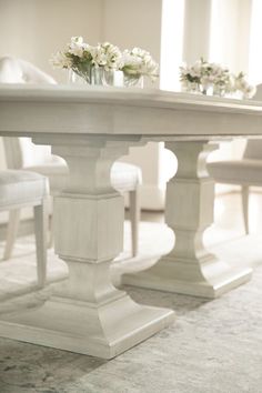 a white table and chairs with flowers in vases on top