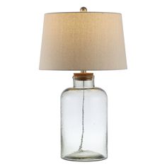 a glass table lamp with a beige shade on it's base and a light bulb in the middle