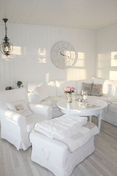 a white living room filled with furniture and a large clock on the wall above it