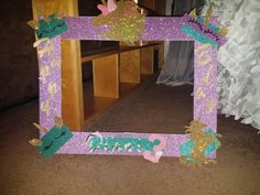 there is a purple and green frame on the floor in front of a mirror that says princess