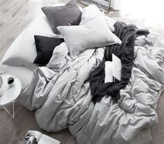 an unmade bed with many pillows and blankets