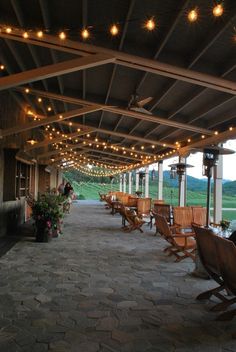 an outdoor covered patio with wooden chairs and string lights