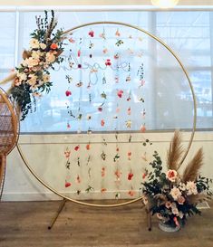 an arrangement of flowers is displayed in front of a large circular display with gold hoop