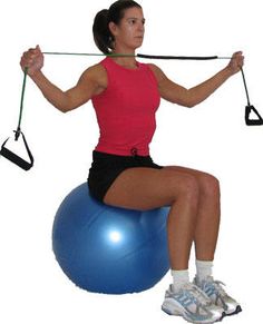 a woman is sitting on an exercise ball and holding the barbell with one leg