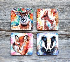 four coasters with animals painted on them sitting next to each other in front of a wooden table