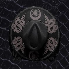 *this item is made by hand each time so placement and print might differ slightly. And a minimal amount of adhesive might show. Also hat band might differ based upon availability. One size fits most with black fringe. I added all items myself by hand and matte black snakes, moons, and sun designs to the top of the brim. Adjustable Black Hat For Music Festival, Adjustable Flat Brim Hat For Music Festival, Black Curved Brim Hat For Festivals, Vintage Black Handmade Hat Bands, Vintage Handmade Black Hat Bands, Handmade Black Fedora With Curved Brim, Handmade Black Costume Hat With Curved Brim, Black Bohemian Hat With Flat Crown, Black Mini Hat With Curved Brim For Festivals