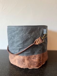 Use this project bag to hold yarn and extras, big enough for the yarn quantity of a sweater! Interior pockets all the way around inside the bag to hold notions & pattern. Bison leather bucket handle is paired with gorgeous 11.5oz tightly woven waxed canvas exterior and organic cotton interior.  The waxed canvas is pliable yet holds its own shape to stand alone. Waxed canvas crinkles as it is used, creating a unique rustic worn-soft look. Bison leather handles are rustic leather, no edge treatmen Outdoor Bucket Bag With Adjustable Strap, Travel Bucket Bag With Waxed Finish, Waxed Canvas Backpack, Yarn Holder, Sweater Bags, Bison Leather, Yarn Cake, Craft Bags, Project Bag