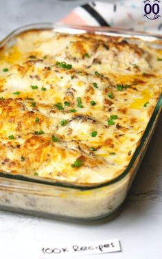 a casserole dish sitting on top of a table with green onions and cheese