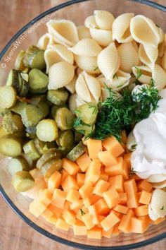 pasta salad ingredients in a bowl with sour cream and pickles on the side, including brussel sprouts