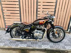 a motorcycle is parked in front of a wooden fence on a sidewalk with a mosaic tile floor