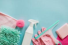 cleaning supplies including gloves, sponges and a spray bottle on a blue background with copy space