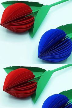 two red and blue paper flowers on top of each other with green leaves attached to them