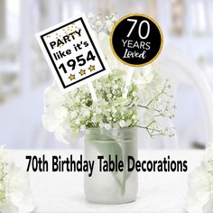 a birthday table decoration with white flowers in a mason jar