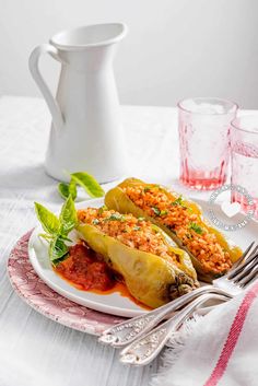 two stuffed poblaas on a plate with sauce and garnishes next to glasses