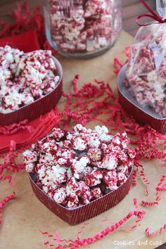 red and white sprinkles in heart shaped tins on table next to candy