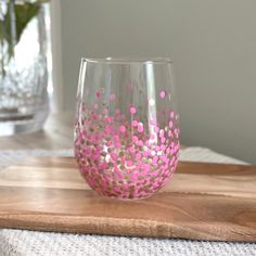 a pink and silver glass sitting on top of a wooden cutting board