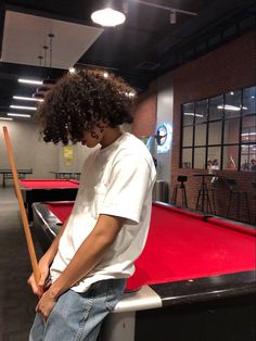 a young man holding a pool stick while standing next to a pool table