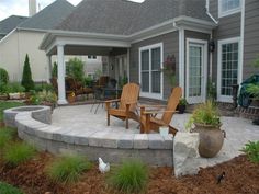 an outdoor patio with chairs and plants in the foreground, next to a house