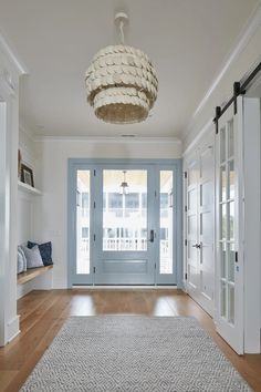 a blue front door is flanked by two white doors and a light fixture hangs from the ceiling