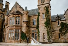 a bride and groom standing in front of an old castle