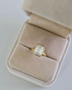 an engagement ring in a velvet box on a white surface with a gold band and diamond center stone